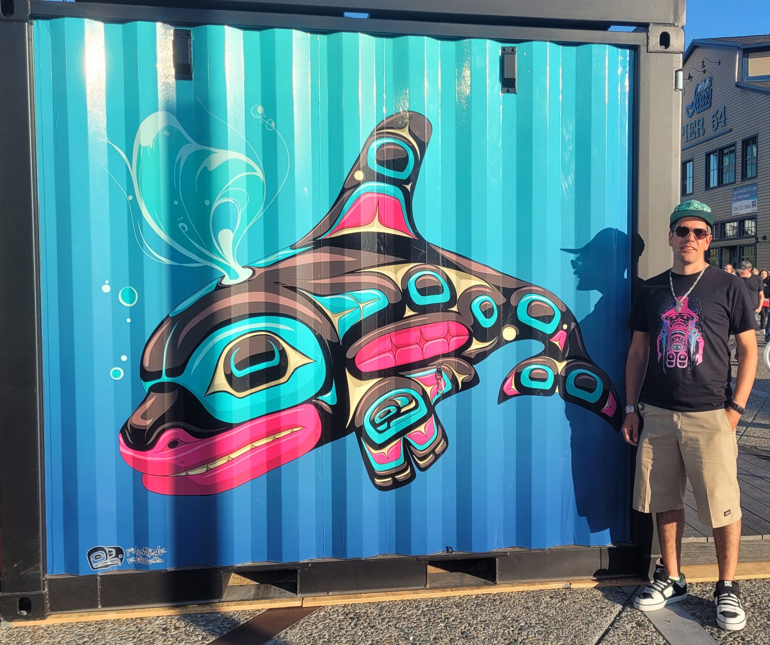 artist standing in front of orca mural