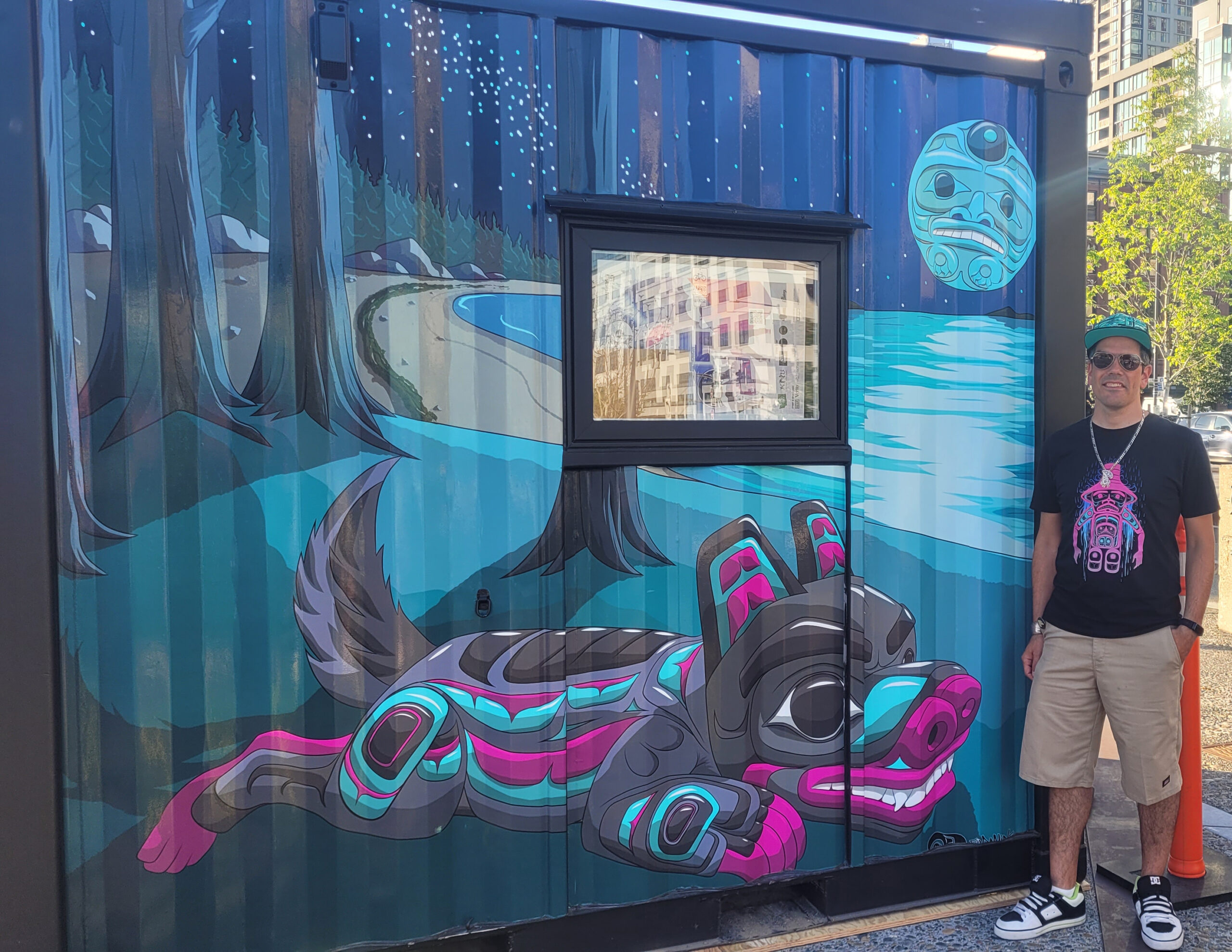 Bill Pfeifer, Jr. stands in front of the Tlingit Wolf mural at the waterfront in seattle